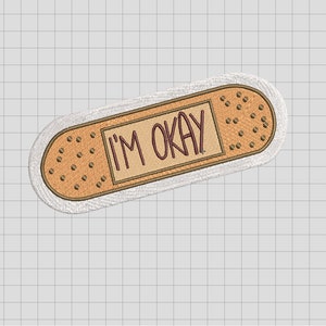 May include: White embroidered patch shaped like a bandage with the text "I'M OKAY" in brown lettering.