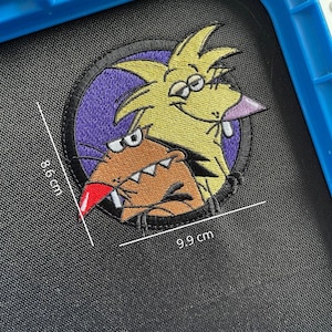 Può includere: Toppa ricamata con castori dei cartoni animati, misura circa 8,6 cm per 9,9 cm. Il design include un castoro giallo con naso viola e un castoro marrone con naso rosso, su un cerchio viola.