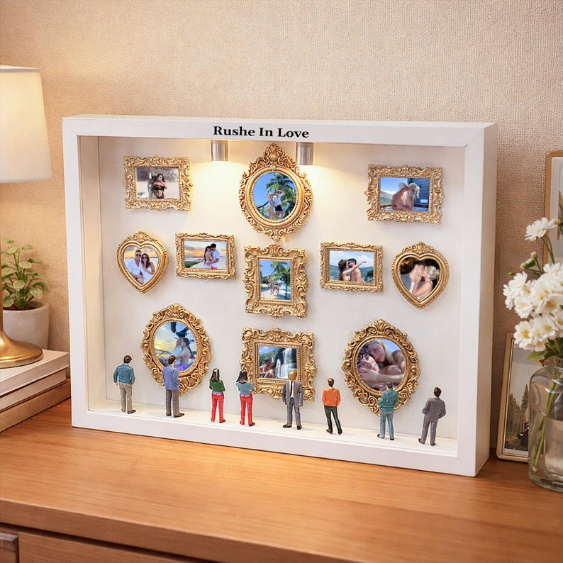 Puede incluir: Una caja blanca con m&uacute;ltiples marcos dorados de diferentes formas y figuras en miniatura. La caja tiene el texto "Rushe In Love" en la parte superior. Los marcos contienen fotograf&iacute;as.
