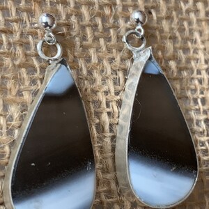 May include: A pair of silver teardrop earrings with black and white agate stones.
