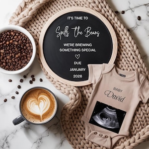 Pode incluir: Anúncio de gravidez com um quadro-negro com a frase "It's Time to Spills the Beans", um body de bebé com "Baby David", uma ecografia, um latte art e uma tigela de grãos de café.