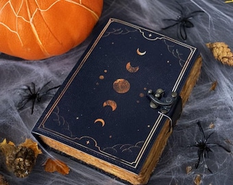 May include: A dark blue leather-bound journal with a gold moon and star design. The journal has a clasp closure and is decorated with a gold border.