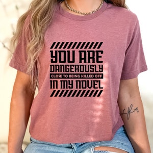 a woman wearing a pink t - shirt that says, you are dangerously close to