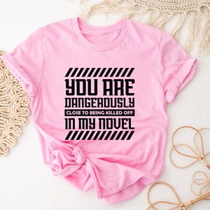 a pink t - shirt that says you are dangerously dangerous in my novel