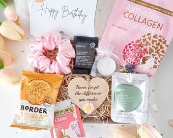 May include: A gift box with a variety of items, including a pink scrunchie, snacks, a face mask, and a card that says "Happy Birthday." The box also contains a wooden heart with the text "Never forget the difference you make."