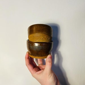 May include: Two brown ceramic bowls stacked on top of each other. The top bowl has the words "Free Range" stamped on the side.