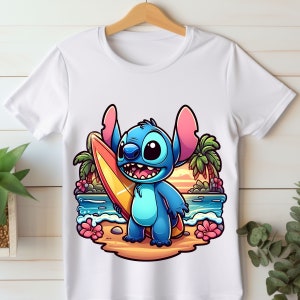 May include: A white t-shirt with a cartoon image of Stitch from Lilo & Stitch holding a surfboard on a beach with palm trees and a sunset in the background.