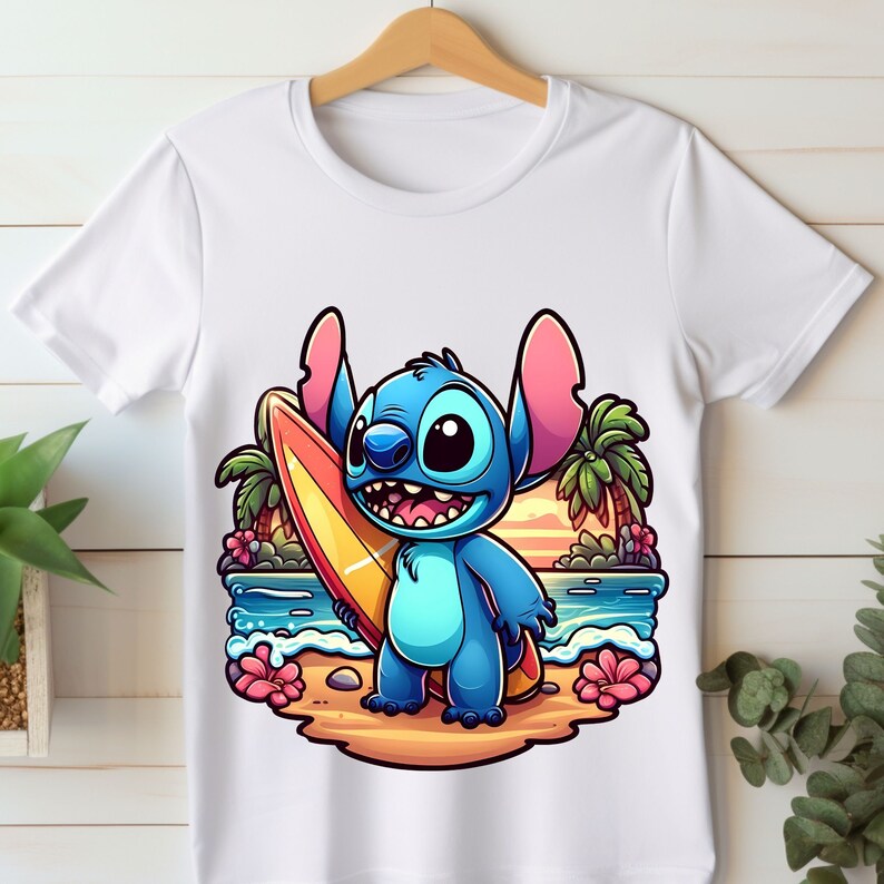 May include: A white t-shirt with a cartoon image of Stitch from Lilo & Stitch holding a surfboard on a beach with palm trees and a sunset in the background.