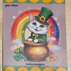 Op de afbeelding: Een kaart met het thema St. Patrick's Day met een witte kat met een groene kaboutermuts en jas, zittend in een pot goud. Een regenboog staat achter de kat. De kaart heeft gouden munten en de tekst "your choice" en "toebeanbudgets".