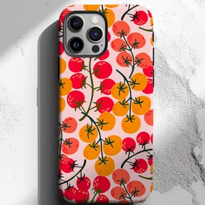 May include: A pink phone case with a pattern of red and orange tomatoes on vines.