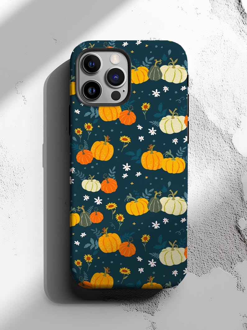 May include: A navy blue phone case featuring a repeating pattern of pumpkins in shades of orange, yellow, and white, along with small white flowers and yellow sunflowers. The case is designed to fit a smartphone.