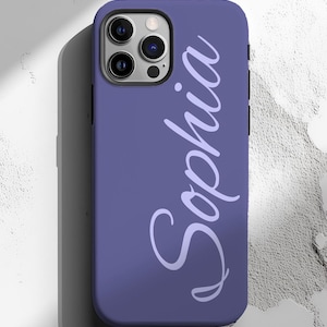 May include: A purple phone case with the name "Sophia" in a cursive font. The case has a matte finish and a black border. The phone's camera lenses are visible at the top.