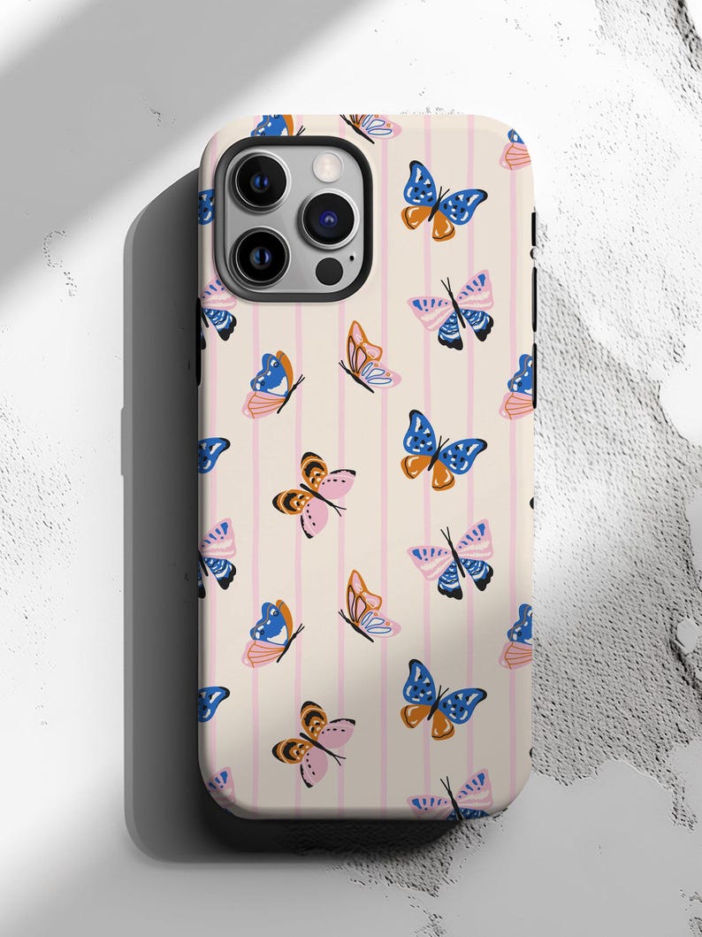 May include: A phone case with a cream background and pink vertical stripes. The case is decorated with a repeating pattern of colorful butterflies in shades of blue, orange, pink, and black.