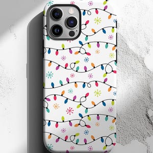 May include: White phone case featuring a repeating pattern of colorful Christmas lights and snowflakes. The lights are in various colors, including red, blue, green, and orange, set against a white background. The case has a glossy finish and a camera cutout.