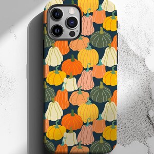 May include: A phone case featuring a repeating pattern of colorful pumpkins in shades of orange, yellow, pink, green, and white against a dark blue background. The case is designed to fit a smartphone.