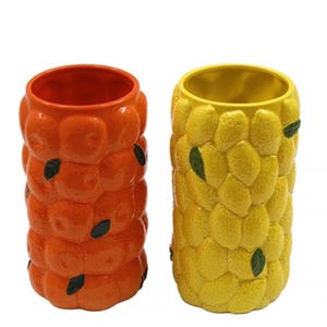 May include: Two ceramic vases, one orange and one yellow, each with a textured, fruit-like design. The orange vase has a tangerine-like pattern with black leaf accents. The yellow vase has a lemon-like pattern with green leaf accents.