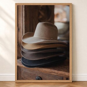 Peut inclure: Une pile de cinq chapeaux en feutre dans des tons variés de brun, de beige et de noir, chacun doté d'un large bord et d'une calotte structurée. Les chapeaux sont empilés soigneusement les uns sur les autres, créant un dégradé de tons neutres.