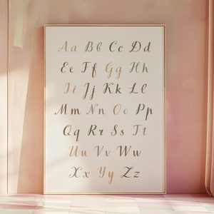 May include: A framed alphabet chart with a white background and gold frame. The letters are written in cursive script in shades of brown and green. The letters are arranged in alphabetical order.