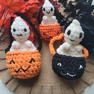 May include: Three crocheted ghost trick or treat bags. The bags are shaped like pumpkins and have smiling faces. The ghosts are white and the pumpkins are orange and black.
