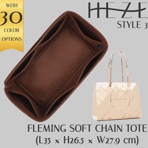 Peut inclure: Un organisateur de sac fourre-tout marron avec plusieurs compartiments, à côté d'un sac fourre-tout beige avec des bretelles en chaîne. L'organisateur mesure 35 cm de long, 26,5 cm de haut et 27,9 cm de large. Le texte "HEZE STYLE 3" et "FLEMING SOFT CHAIN TOTE" est inclus.