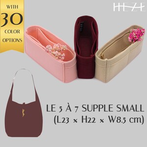 Puede incluir: Un bolso burdeos con un diseño de rayo dorado, junto con tres organizadores de fieltro en rosa, burdeos y beige. Los organizadores están adornados con flores. Texto: "LE 5 À 7 SUPPLE SMALL (L23 x H22 x W8.5 cm)" y "WITH 30 COLOR OPTIONS."