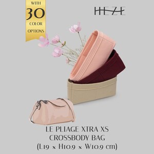 May include: A light pink, dark red, and beige felt bag organizer set with multiple compartments. Below, a light pink crossbody bag is labeled LE PLIAGE XTRA XS CROSSBODY BAG with dimensions L19 x H10.9 x W10.9 cm. The text HEZE and WITH 30 COLOR OPTIONS appear.