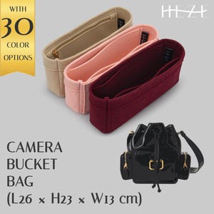 May include: Three felt bag inserts in beige, pink, and burgundy. The inserts are designed to fit inside a camera bucket bag. The text "HEZE" is printed in white on a black background. The text "WITH 30 COLOR OPTIONS" is printed in white on a gold background. The text "CAMERA BUCKET BAG (L26 x H23 x W13 cm)" is printed in black on a white background.
