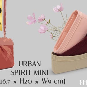 May include: Three felt bag organizers in light pink, dark burgundy, and beige. A graphic of a red bag is shown with text stating WITH 30 COLOR OPTIONS, URBAN SPIRIT MINI, and dimensions of L16.7 x H20 x W9 cm. A sprig of pink flowers is visible.