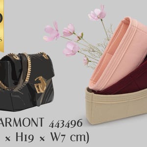 May include: A black handbag with a gold chain strap and a gold clasp, accompanied by three felt purse organizers in light pink, dark red, and beige. Text reads: WITH 30 COLOR OPTIONS, MARMONT 443496 (L31 x H19 x W7 cm). Pink flowers are visible.