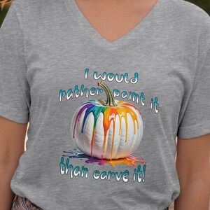 K&ouml;nnte beinhalten: Graues V-Ausschnitt-T-Shirt mit einem wei&szlig;en K&uuml;rbis, der mit Regenbogenfarben bemalt ist. Die Farbe tropft herunter. Der Text "I would rather paint it than carve it!" steht in Blau und Wei&szlig; geschrieben.