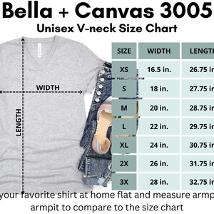 K&ouml;nnte beinhalten: Hellgraues Bella + Canvas 3005 Unisex-V-Ausschnitt-T-Shirt mit Gr&ouml;&szlig;entabelle. Die Tabelle zeigt Ma&szlig;e f&uuml;r die Gr&ouml;&szlig;en XS bis 3X, mit Breiten von 41,9 cm bis 71,1 cm und L&auml;ngen von 67,9 cm bis 83,2 cm.