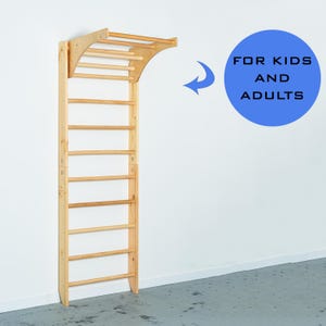 K&ouml;nnte beinhalten: Eine Wandmontage-Klimmzugstange aus Holz mit einer Leiter. Die Stange ist oben gew&ouml;lbt und hat eine helle Holzoptik. Der Text "FOR KIDS AND ADULTS" ist in Schwarz auf einem blauen Kreis geschrieben.