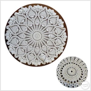 May include: A white crocheted doily with a delicate, intricate design. The doily is circular and has a scalloped edge.