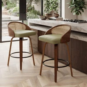 May include: Two swivel bar stools with dark wood frames, light green upholstered seats, and curved cane backrests. Each stool features four tapered legs connected by a circular black metal footrest, providing a stable base for seating.