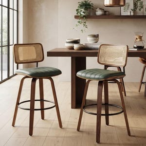 May include: Two swivel bar stools featuring dark wood frames, green upholstered seats with horizontal channel tufting, and rectangular backrests with natural woven cane webbing. Each stool includes a circular black metal footrest ring.