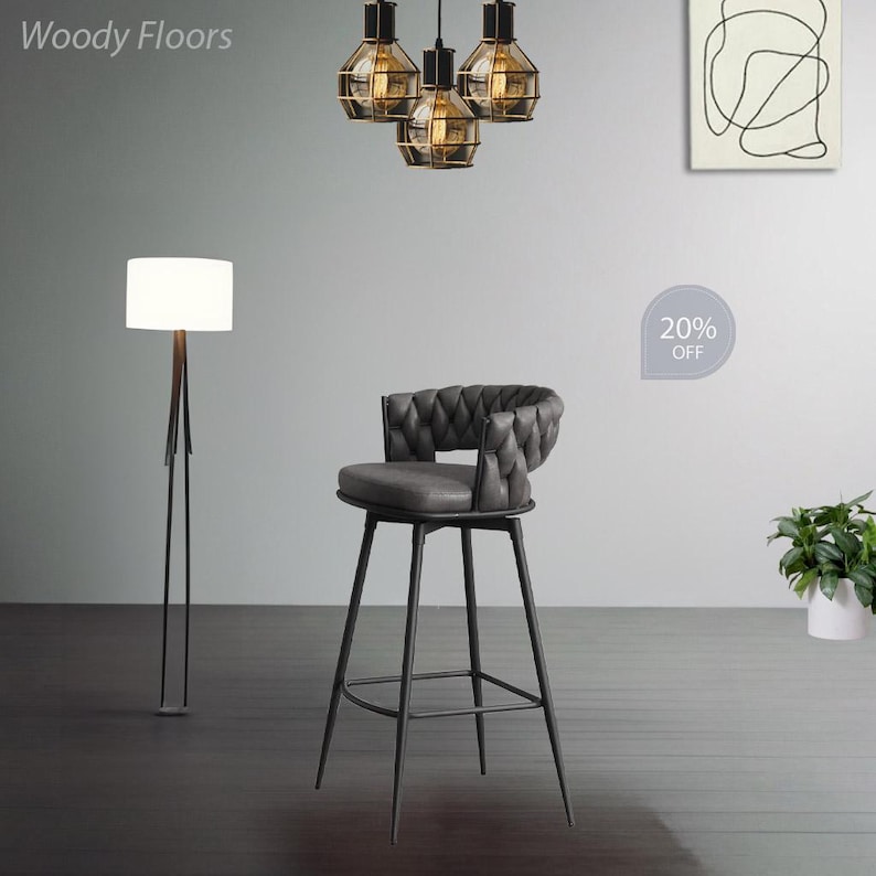 May include: A black metal bar stool with a grey upholstered seat and a tufted back. The stool has a footrest and is 20% off.