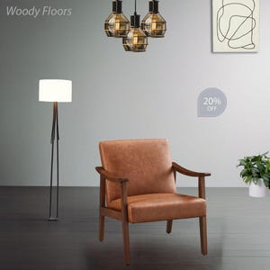 May include: A brown leather armchair with wooden arms and legs. A modern floor lamp with a white lampshade stands to the left. Above, three pendant lights with geometric metal frames hang from the ceiling. The text "20% OFF" is visible.