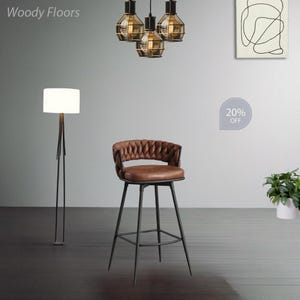 May include: A brown leather bar stool with a black metal frame and a woven back. The stool has a footrest and is 20% off.