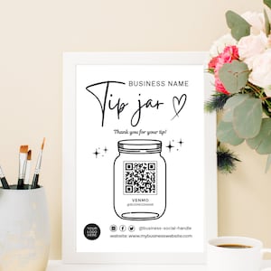 May include: A black and white sign with the text "Tip jar" and a heart. The sign also includes a QR code and the text "VENMO @BUSINESSNAME".