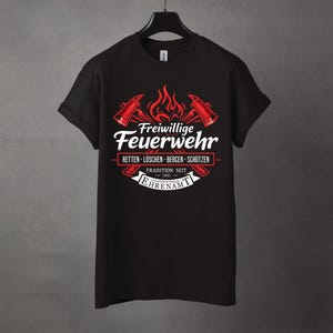May include: Black t-shirt featuring a red and white graphic. The design includes crossed axes, flames, and the German text "Freiwillige Feuerwehr" (Volunteer Fire Department). Additional text includes "RETTEN - L&Ouml;SCHEN - BERGEN - SCH&Uuml;TZEN" and "TRADITION SEIT 1841".