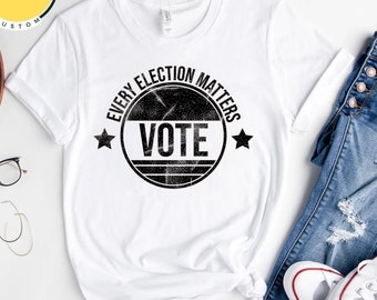 Puede incluir: Camiseta blanca con un gráfico circular negro desgastado que dice "Every Election Matters Vote" con una estrella a cada lado del círculo.