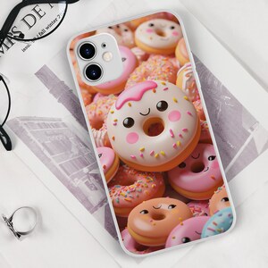 May include: A white phone case with a colorful donut design. The donuts are pink, white, and brown with sprinkles and frosting. Some of the donuts have happy faces.