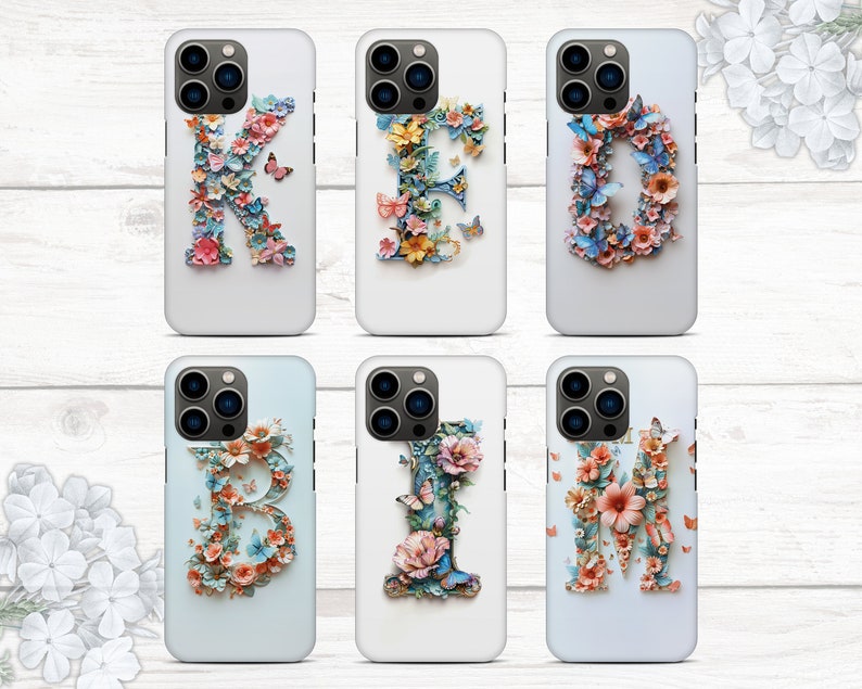 May include: Six iPhone cases with floral designs and letters K, I, M, B, E, and I. The cases are white with a clear plastic back and a floral design that spells out the word "KIMBIE".