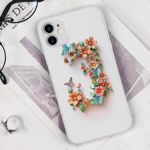 May include: White phone case with a floral design featuring a large letter 'C' made of pink, orange, and yellow flowers with blue butterflies.