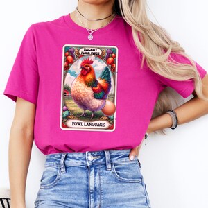 Puede incluir: Una camiseta rosa con un gráfico de un gallo con el texto "FLUCKEY FLUCK, FLUCK" y "FOWL LANGUAGE".