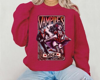 May include: A maroon sweatshirt featuring a vintage-style graphic of a vampire couple with the text "Vampires Suck" in a decorative frame. The design includes a male vampire in a black suit and a female vampire in a red and black dress.