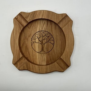 Könnte beinhalten: Ein Holztablett mit einem geschnitzten Lebensbaum-Design. Das Tablett hat eine abgerundete Form mit vier Vertiefungen am Rand.