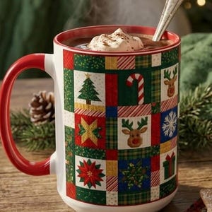 May include: A ceramic mug with a red handle and a colorful patchwork pattern featuring Christmas trees, reindeer, candy canes, snowflakes, and poinsettias. The mug is filled with a hot beverage topped with whipped cream and a silver spoon.