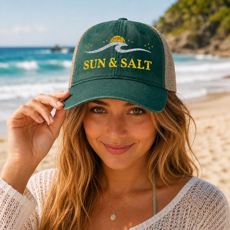 May include: A dark green baseball cap with a mesh back, featuring a graphic of a silver wave and a yellow sun above the text SUN & SALT in yellow lettering. The cap has a structured front panel and a curved brim, designed with a casual aesthetic.