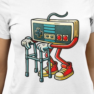 May include: White t-shirt featuring a cartoon video game controller character. The controller has red arms and legs, wearing red sneakers with yellow laces. It is using a walker. The controller has a black cord.